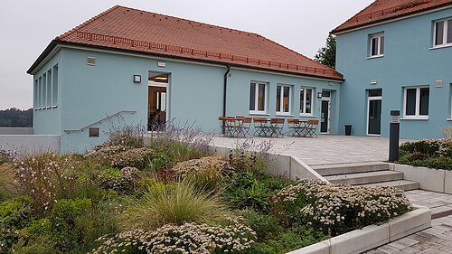 Ein türkises Haus mit einem kleinen Biergarten vor dem Haus.